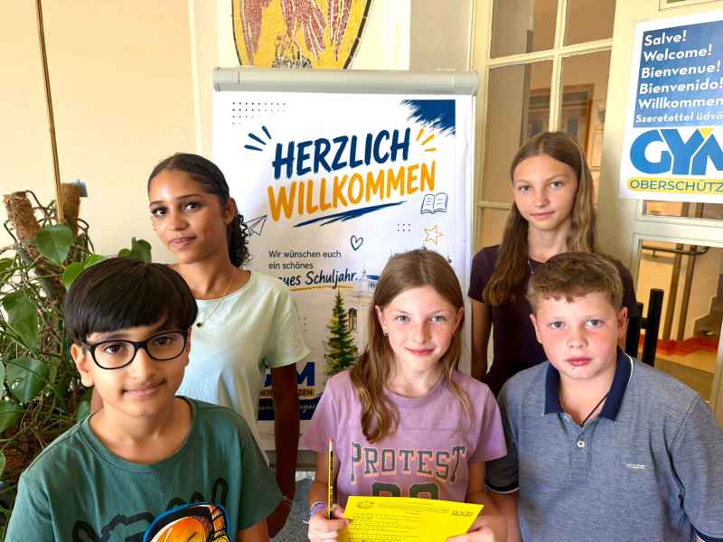 Schuljahr: Fünf Kinder stehen vor einer Willkommens-Tafel in Österreich.